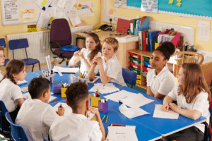 Children at primary school sat around a table working and talking