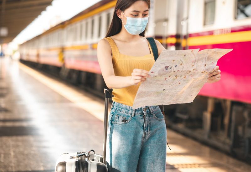 Woman traveler with bag, luggage, suitcase arrival   during traveling, travel, trip for woman concept, say hi, good bye to friend..trip in summer with face mask for protection by infection from Coronavirus, Covid-19